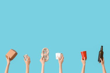 Mavi arka planda farklı çöpleri tutan kadın eller. Geri dönüşüm kavramı