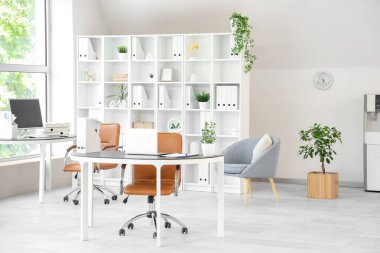 Çalışma alanları, raf ünitesi ve koltukları olan açık uzay ofisinin içi