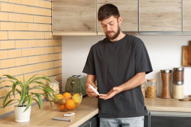 Mutfakta tükenmez kalem kullanan şeker hastası genç bir adam.