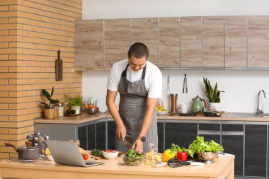 Genç adam mutfakta domates kesiyor.