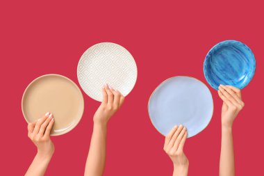 Kırmızı arkaplanda boş tabakları tutan eller