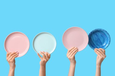 Mavi arkaplanda boş tabakları tutan eller