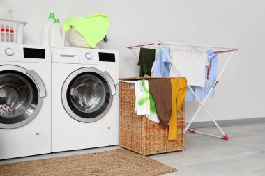 Çamaşır makinesi, çamaşır sepeti ve kurutuculu hafif banyonun içi.