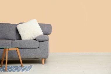 Bej duvarın yanında rahat bir kanepe ve sehpa var.