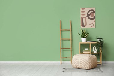 Raflar, merdiven ve pouf yeşil duvarın yanında.