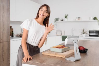 Elmalı turtayla mutfakta el sallayan genç kadın.