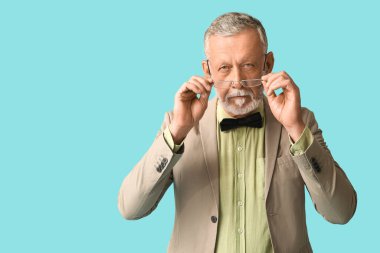 Mavi arka planda şık papyonlu yakışıklı olgun bir adam.