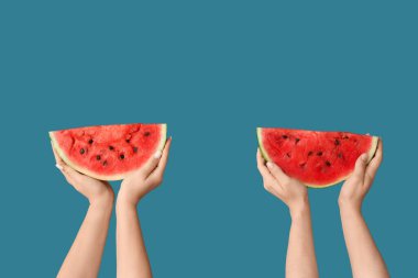 Mavi arka planda tatlı karpuz dilimleri olan kadın elleri