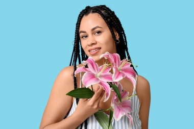 Mavi arka planda pembe zambak çiçekleri olan güzel bir Afro-Amerikalı kadın.