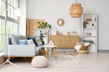 Pencerenin yanında gri kanepesi ve sehpası olan modern oturma odasının içinde.