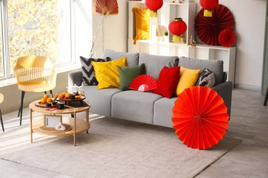 Çin Yeni Yıl kutlamaları için gri kanepe, masa ve dekorla aydınlık oturma odasının içinde.