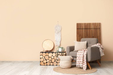 Ahşap masa ve bej duvarın yanında katlanır ekran ile yumuşak gri koltuk