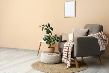 Yumuşak puflu şık gri koltuk ve bej duvarın yanında bitkiler.