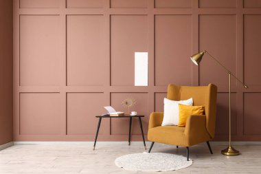 Yumuşak yastıklı rahat sarı koltuk ve kahverengi duvarın yanında yer lambası.