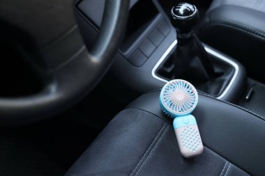 Minik elektrikli vantilatör koltukta.