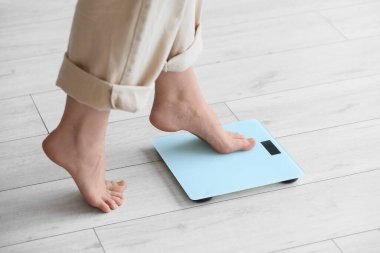 Mutfaktaki terazinin ağırlığını ölçen kadının ayakları, yakın plan.