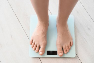 Evdeki terazide ağırlığını ölçen kadının ayakları, üst manzara.