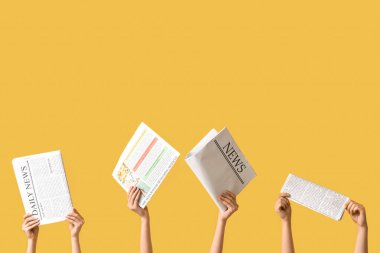 Sarı arka planda gazeteleri olan kadın eller.