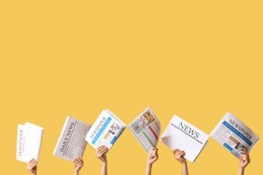 Sarı arka planda gazeteleri olan kadın eller.