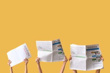 Sarı arka planda gazeteleri olan kadın eller.