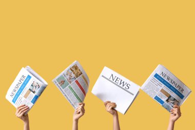 Sarı arka planda gazeteleri olan kadın eller.