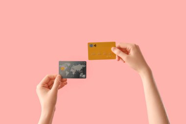 Female hands with credit cards on pink background