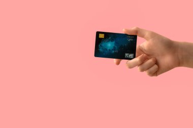Pembe arka planda kredi kartı olan bir kadın.