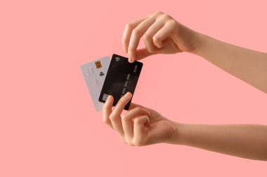 Female hands with credit cards on pink background
