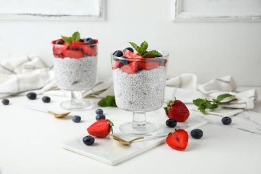 Bardaklar dolusu taze meyveli Chia tohumu pudingi ve beyaz arkaplanda nane şekeri.