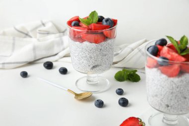 Bardaklar dolusu taze meyveli Chia tohumu pudingi ve beyaz arkaplanda nane şekeri.