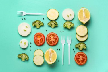 Turkuaz arka planda taze sebze ve plastik çatallı kompozisyon, yakın plan.