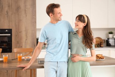 Mutfakta masanın yanında sarılan genç çift.