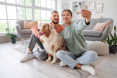 Avustralyalı çoban köpeği olan genç çift evde selfie çekiyor.