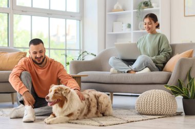 Evde dizüstü bilgisayar kullanan Avustralyalı çoban köpeği ve kız arkadaşı olan genç adam.