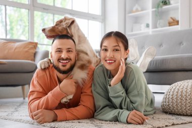 Avustralya çoban köpeği olan genç çift evdeki halıda yatıyor.