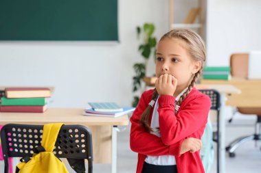 Sınıfta tırnaklarını yiyen küçük bir kız öğrenci.