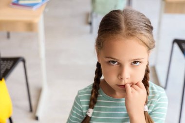 Sınıfta tırnaklarını yiyen küçük kız, yakın plan.