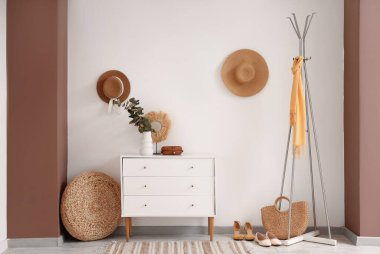 Modern koridorun içinde elbise askısı, tuvalet, ayakkabı ve beyaz duvarda asılı şapkalar var.