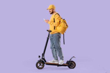 Leylak arka planında cep telefonu olan elektrikli scooter kullanan genç bir adam.