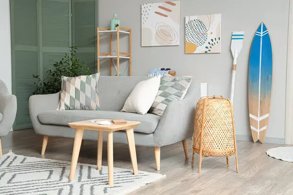 Gri kanepe ve sörf tahtasıyla modern oturma odasının içinde.