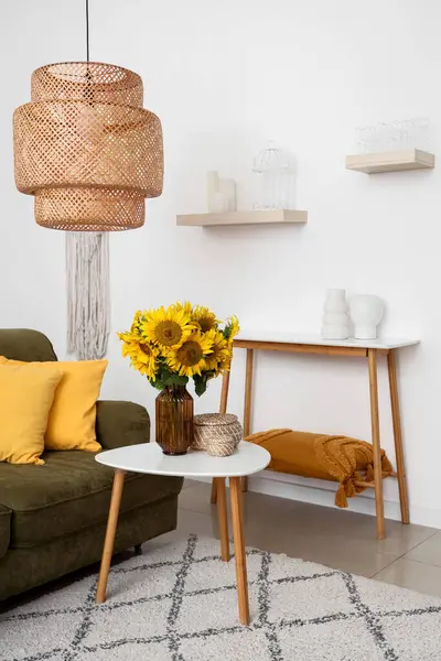 Yeşil kanepeli şık bir oturma odası ve sehpanın üzerinde güzel ayçiçekleri buketi, yakın plan.