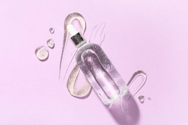 Bir şişe kozmetik ürünü ve pembe arka planda kozmetik jel örnekleri, yakın plan.