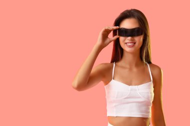 Pembe arka planda modern siyah VR gözlüklü güzel bir kadın.