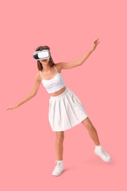 Pembe arka planda modern VR gözlüklü güzel bir kadın.