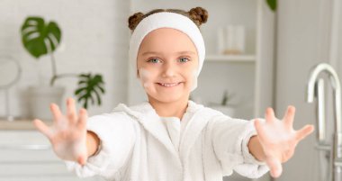 Küçük kız ellerini banyoda yıkıyor.