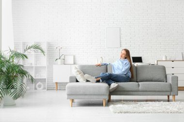 Oturma odasındaki kanepede yatan genç kadın.