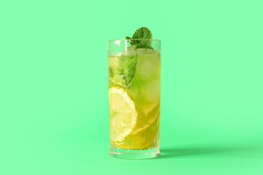 Limon dilimli bir bardak lezzetli limonata ve yeşil arkaplanda nane.