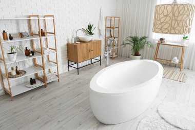 Küvetli modern banyo, çekmeceler, raf ünitesi ve lamba.