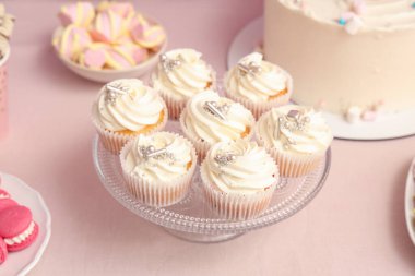 Tatlı standı, lezzetli beyaz kekler ve pembe masadaki doğum günü partisi için diğer tatlılar.