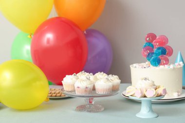 Beyaz duvara karşı doğum günü partisi için farklı şekerlemeler ve balonlar.